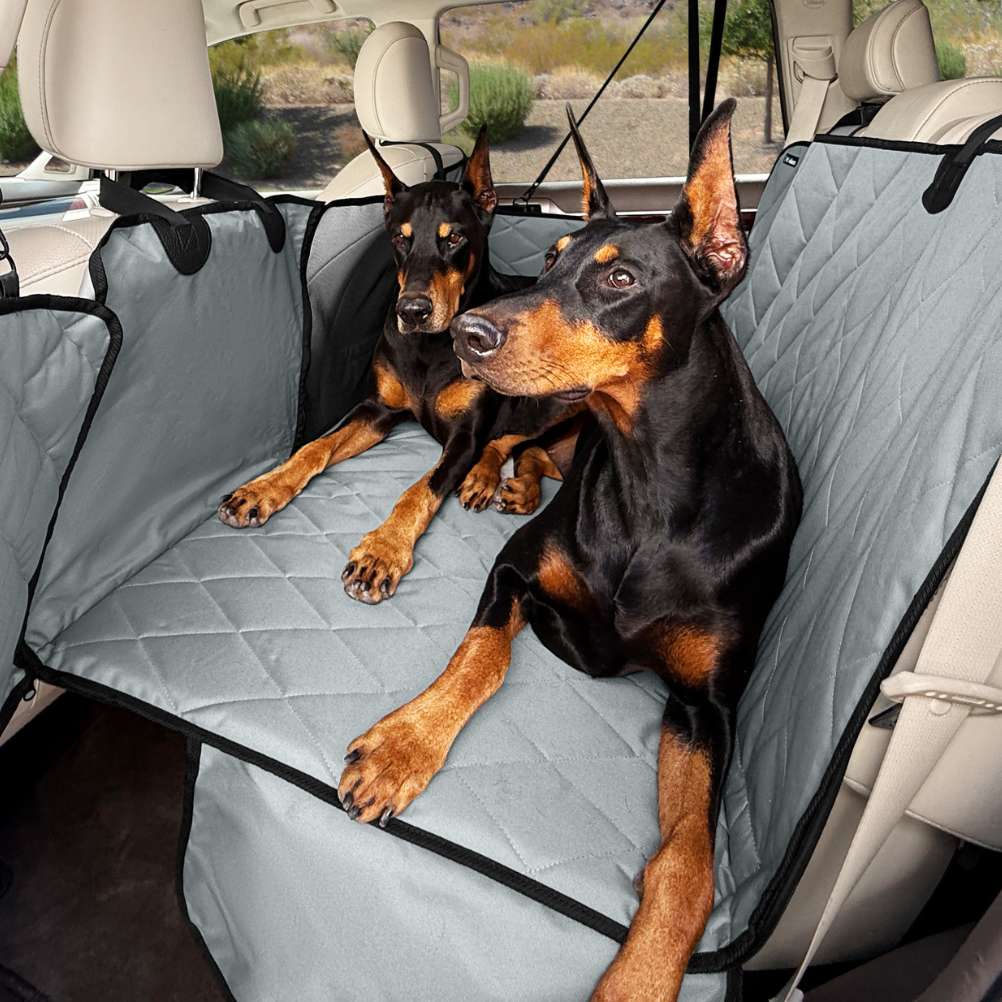 Two Dobermans lying on a grey 4Knines hard bottom extender in a truck's back seat