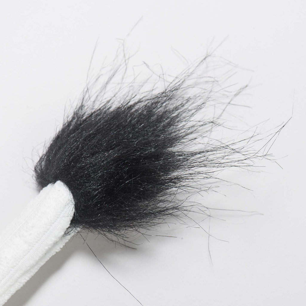 Close-up of the cow toy's white corduroy tail ending in a black furry tuft