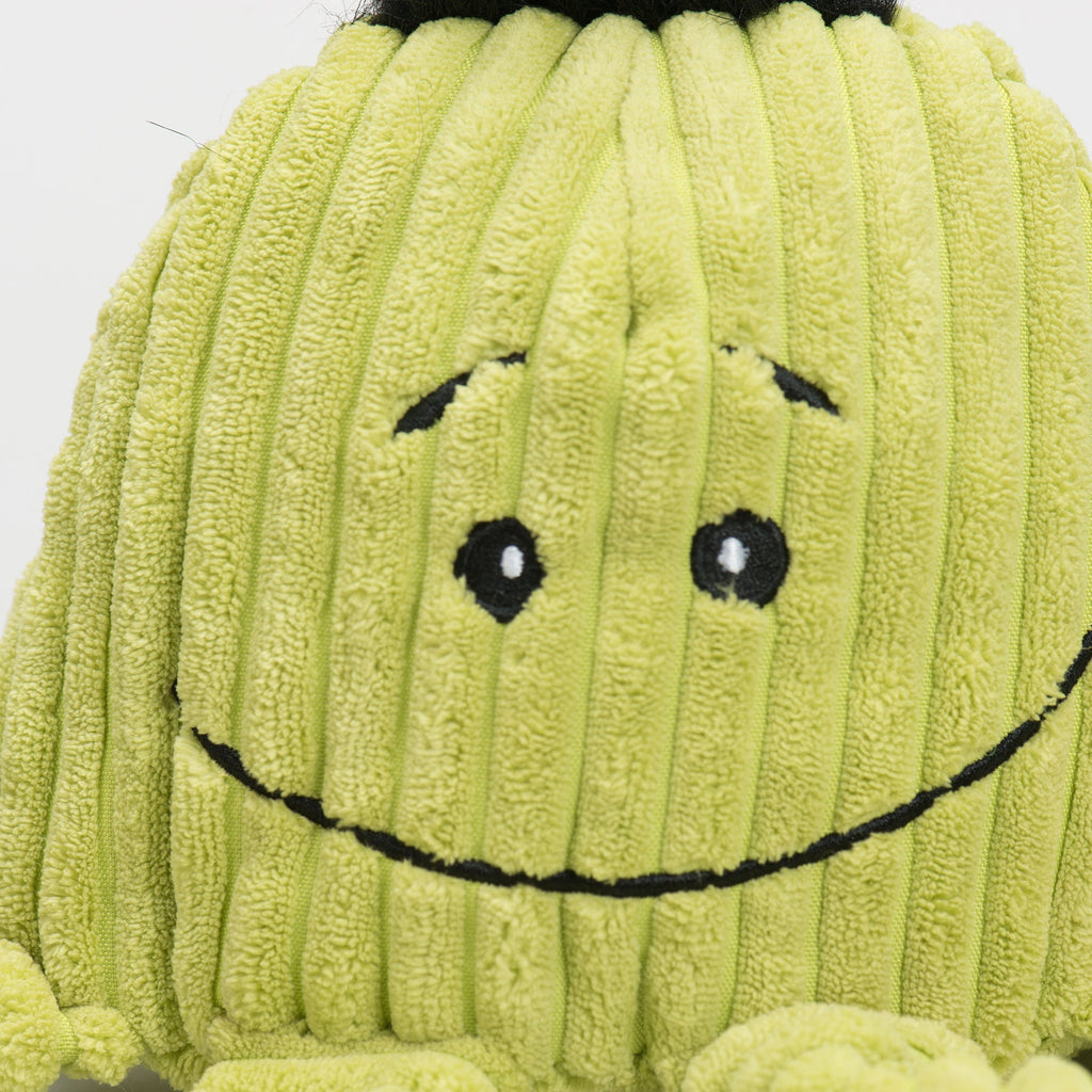 Close-up of the green octopus toy's stitched smiling face and corduroy ribs