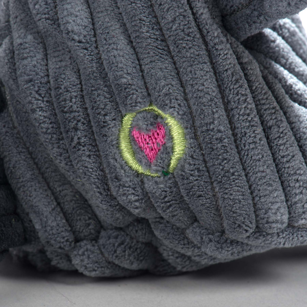 Close-up of the embroidered heart patch on the raccoon toy's corduroy body