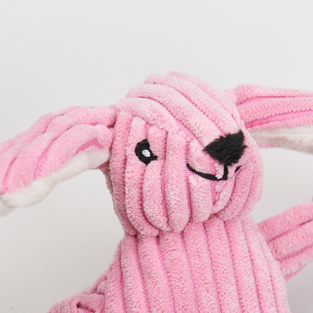 Close-up of the pink bunny toy's embroidered face and corduroy texture