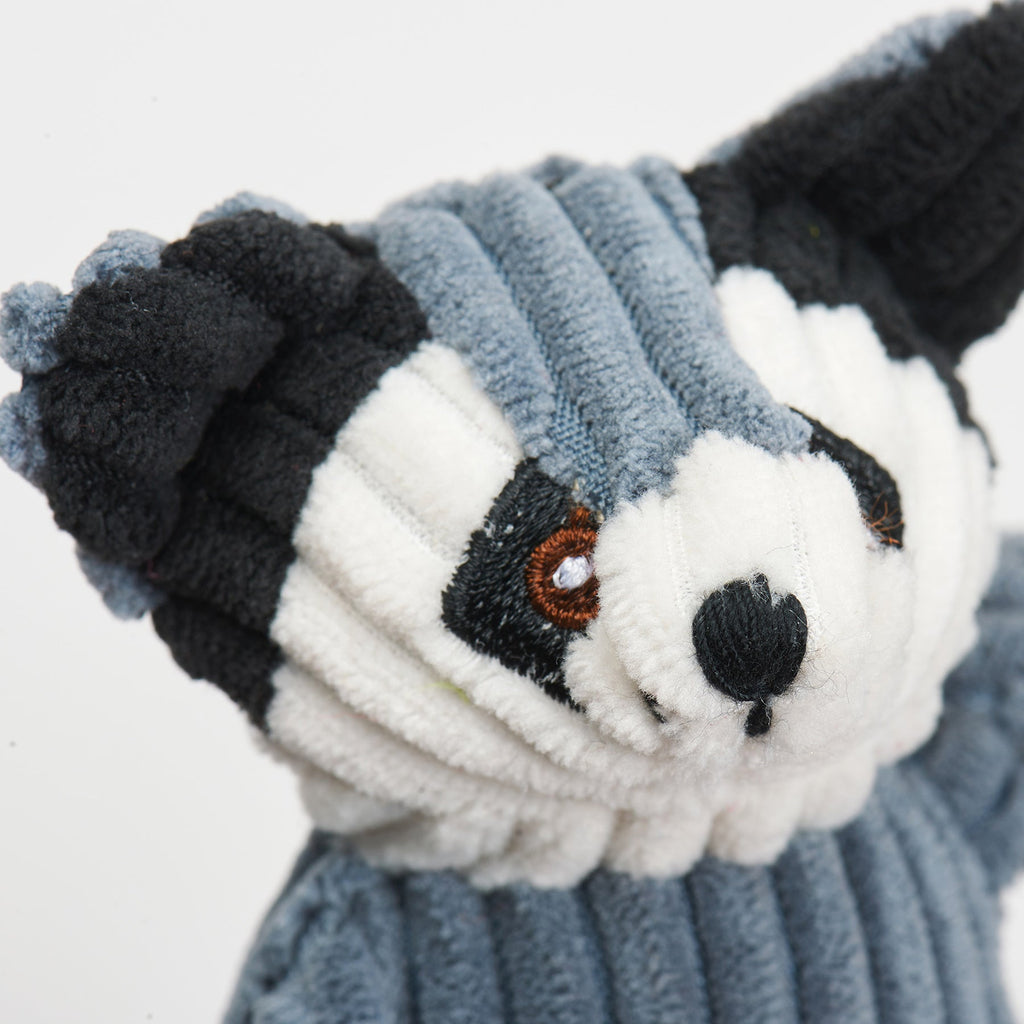 Close-up of the raccoon toy's embroidered eyes and corduroy face