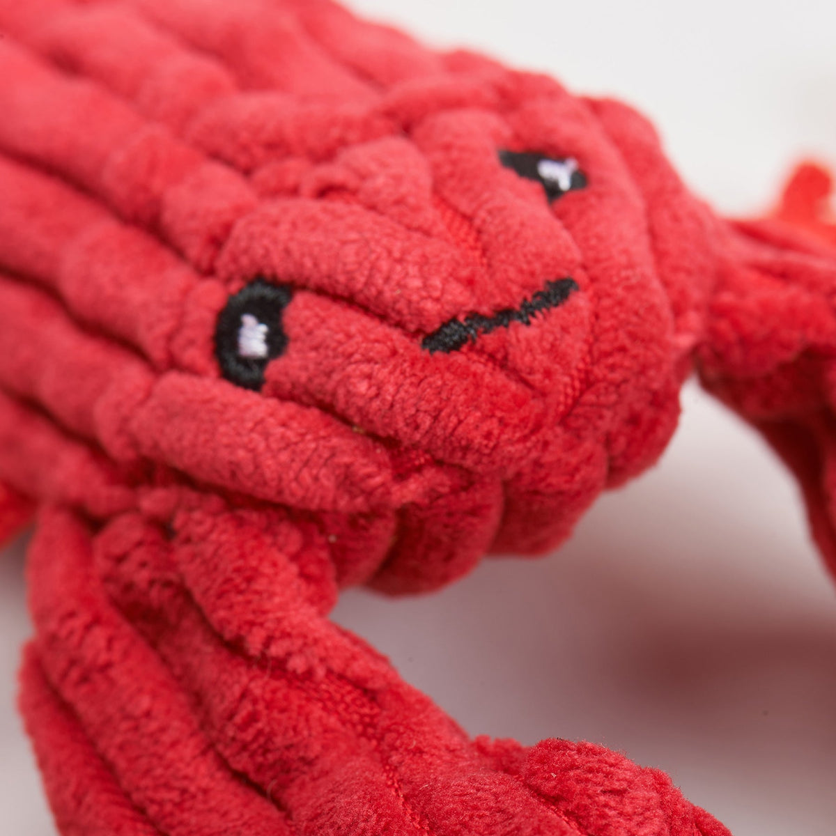 Close-up of the red lobster toy's corduroy face and stitched eyes