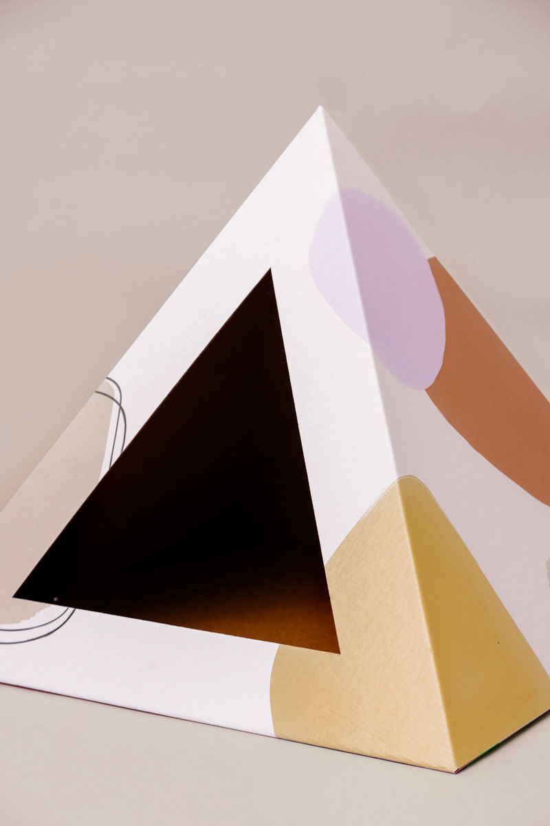 Empty Abstract cardboard cat pyramid with lilac, terracotta and mustard shapes on white