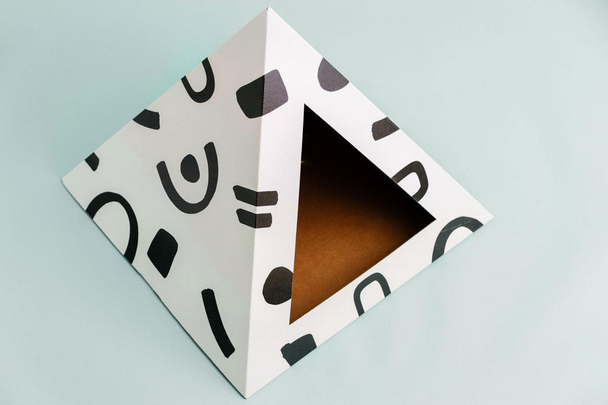 Doodle-pattern cardboard cat pyramid seen from above