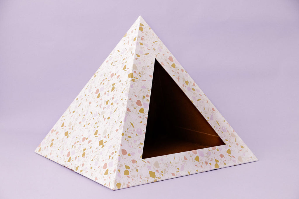 Empty terrazzo-pattern cardboard cat pyramid on a lilac background
