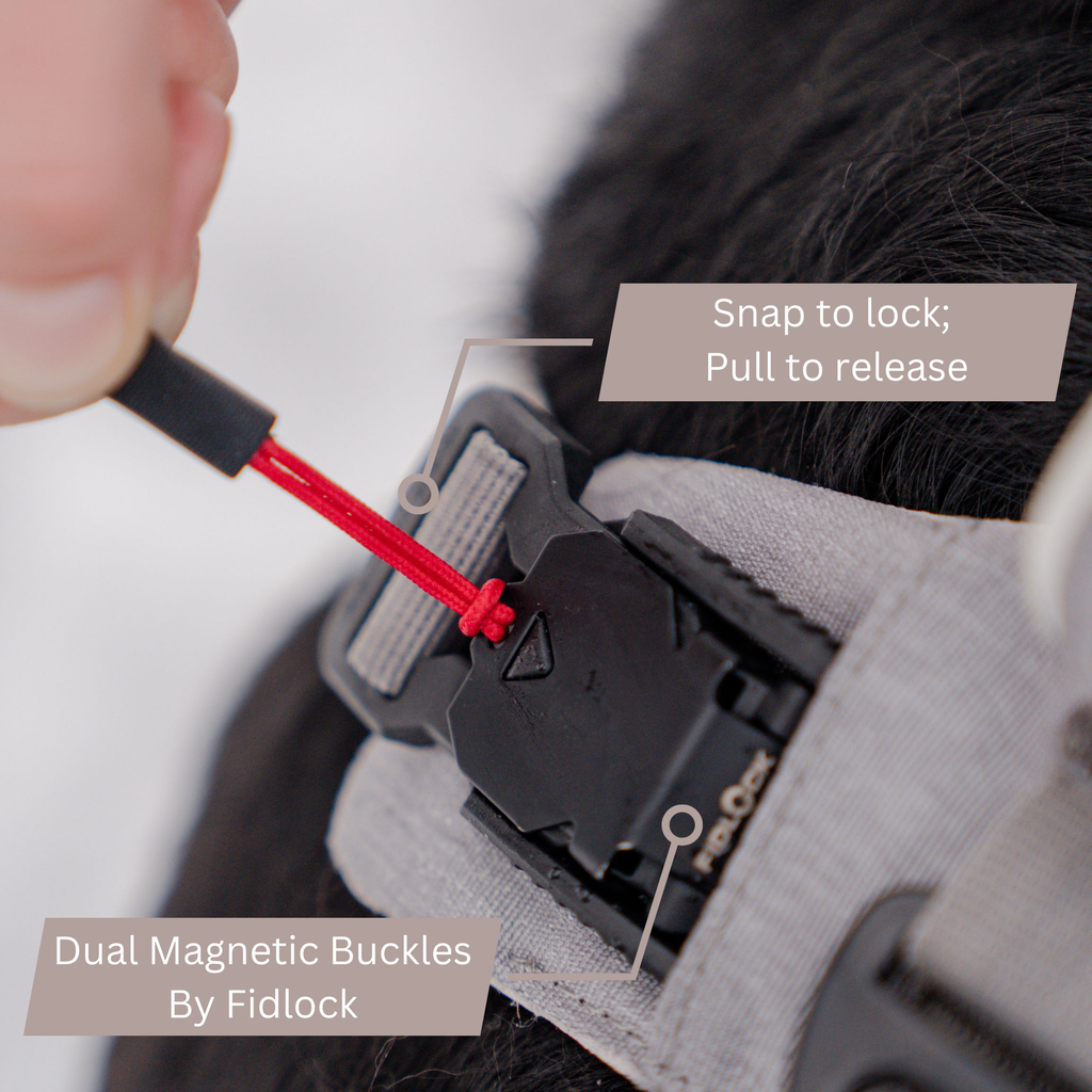 Hand pulling the red tab to open the harness's magnetic buckle