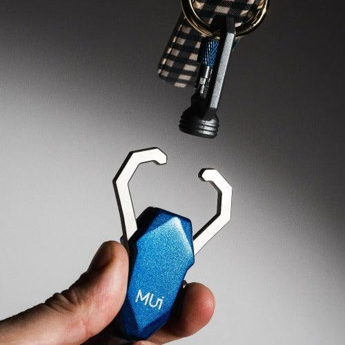 Hand holding the blue magnetic latch below a collar's metal ring