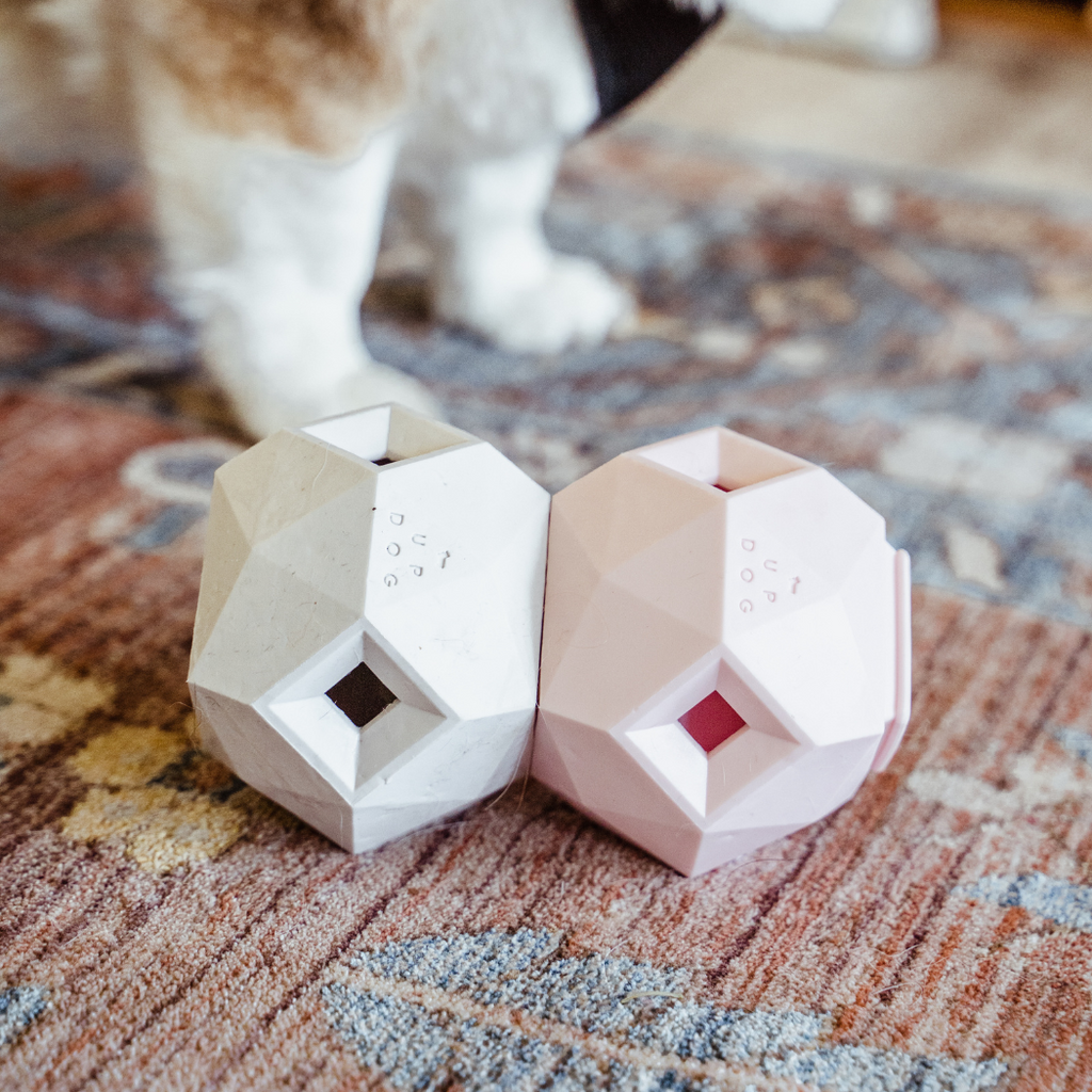 White and pink geometric treat toys on a patterned rug
