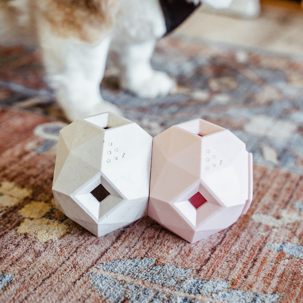 White and pink geometric treat toys on a patterned rug