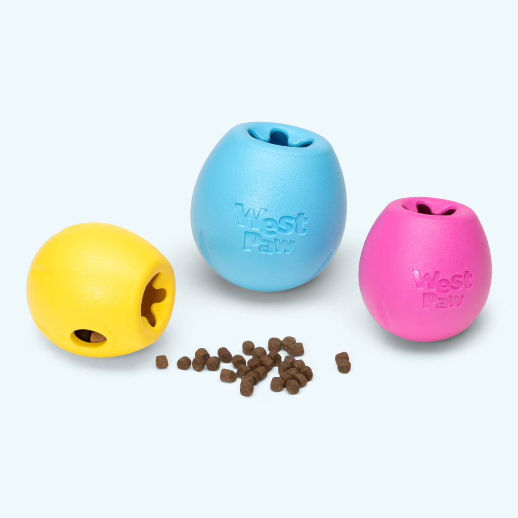 Yellow, blue and pink egg-shaped treat toys with kibble