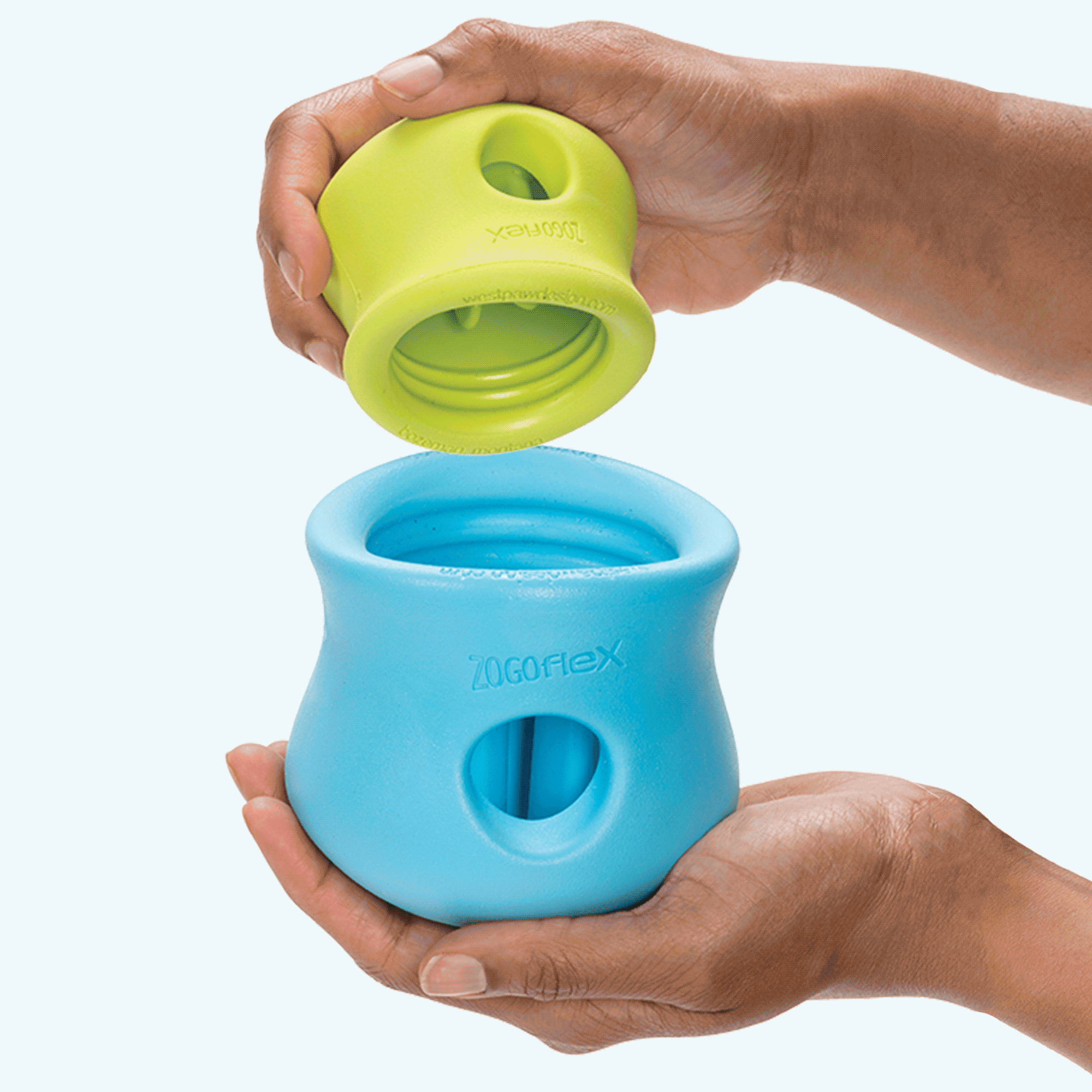 Hands fitting a small lime treat toy inside a larger blue one