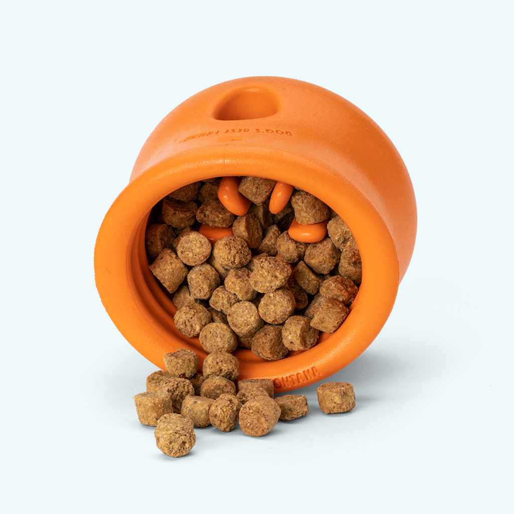 Orange treat toy on its side with kibble spilling out