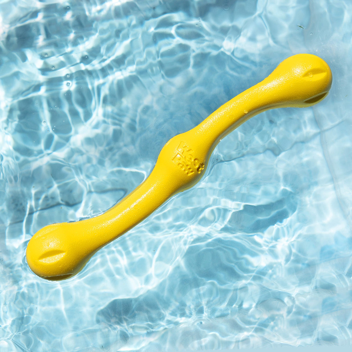 Yellow stick-shaped fetch toy floating in a pool